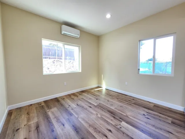 an empty room with wooden floor and windows