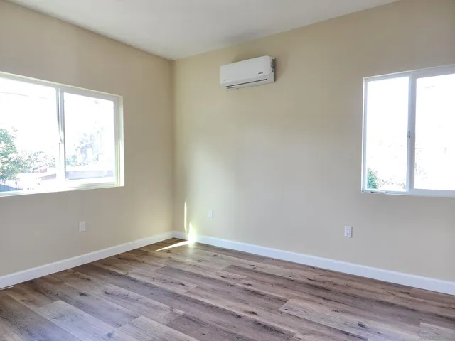 an empty room with wooden floor and windows