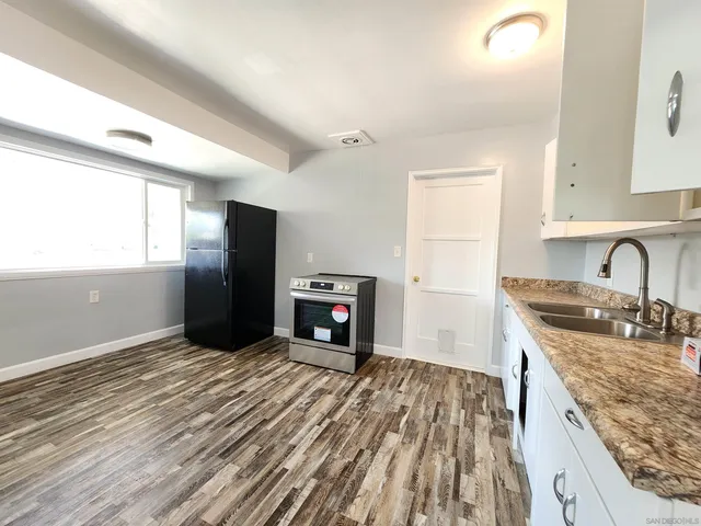 a kitchen with granite countertop a sink stove and refrigerator