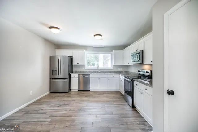 a large kitchen with stainless steel appliances a refrigerator and a stove top oven