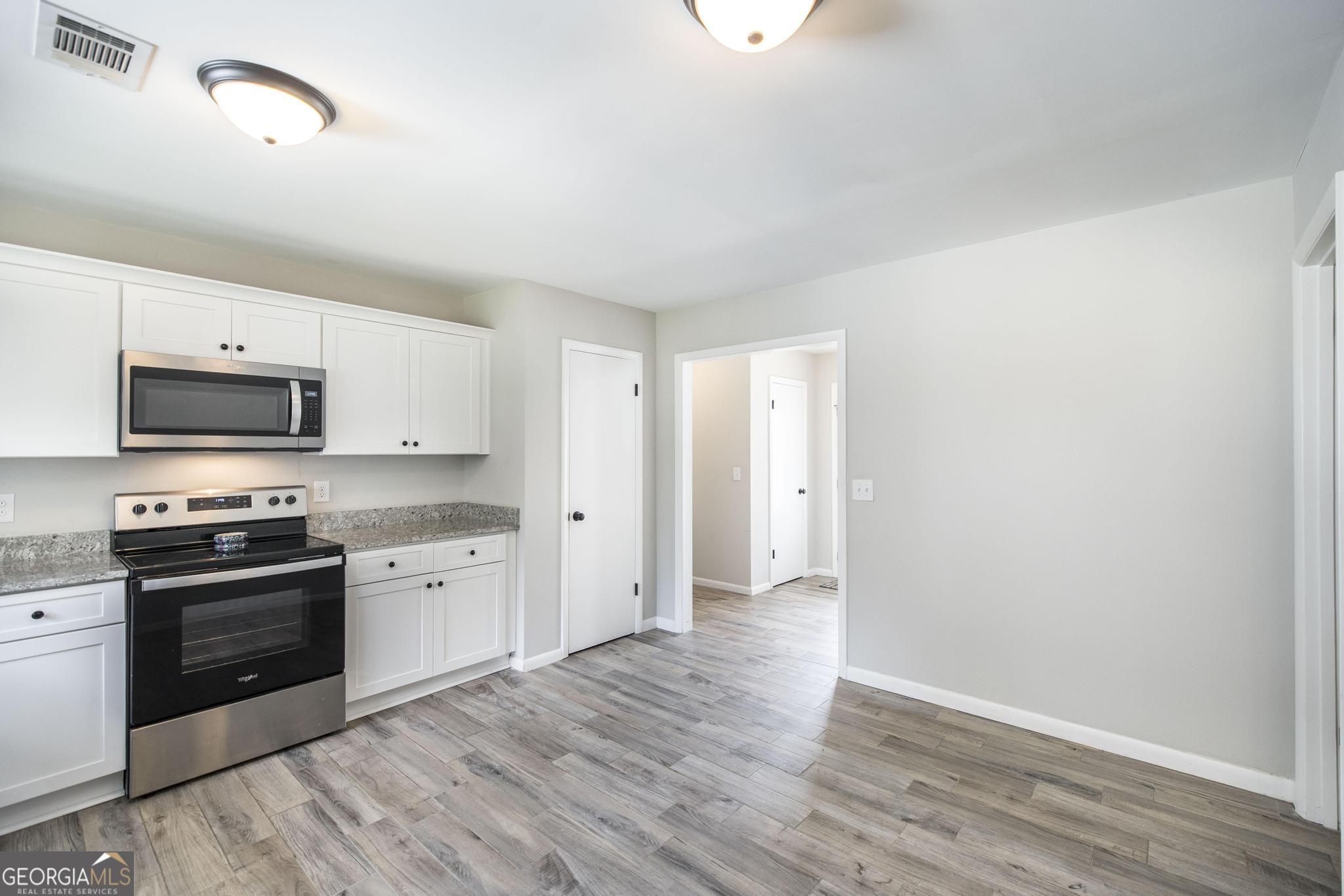 221 Gilchrist Drive Warner Robins, GA 31093 - Photo 14 of 33 a kitchen with stainless steel appliances granite countertop a stove top oven a sink and dishwasher with wooden floor
