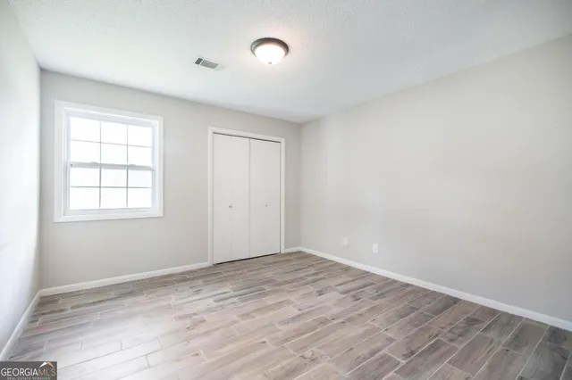 an empty room with wooden floor and windows
