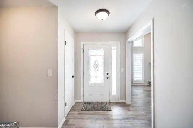 a view of a hallway with wooden floor and a bathroom