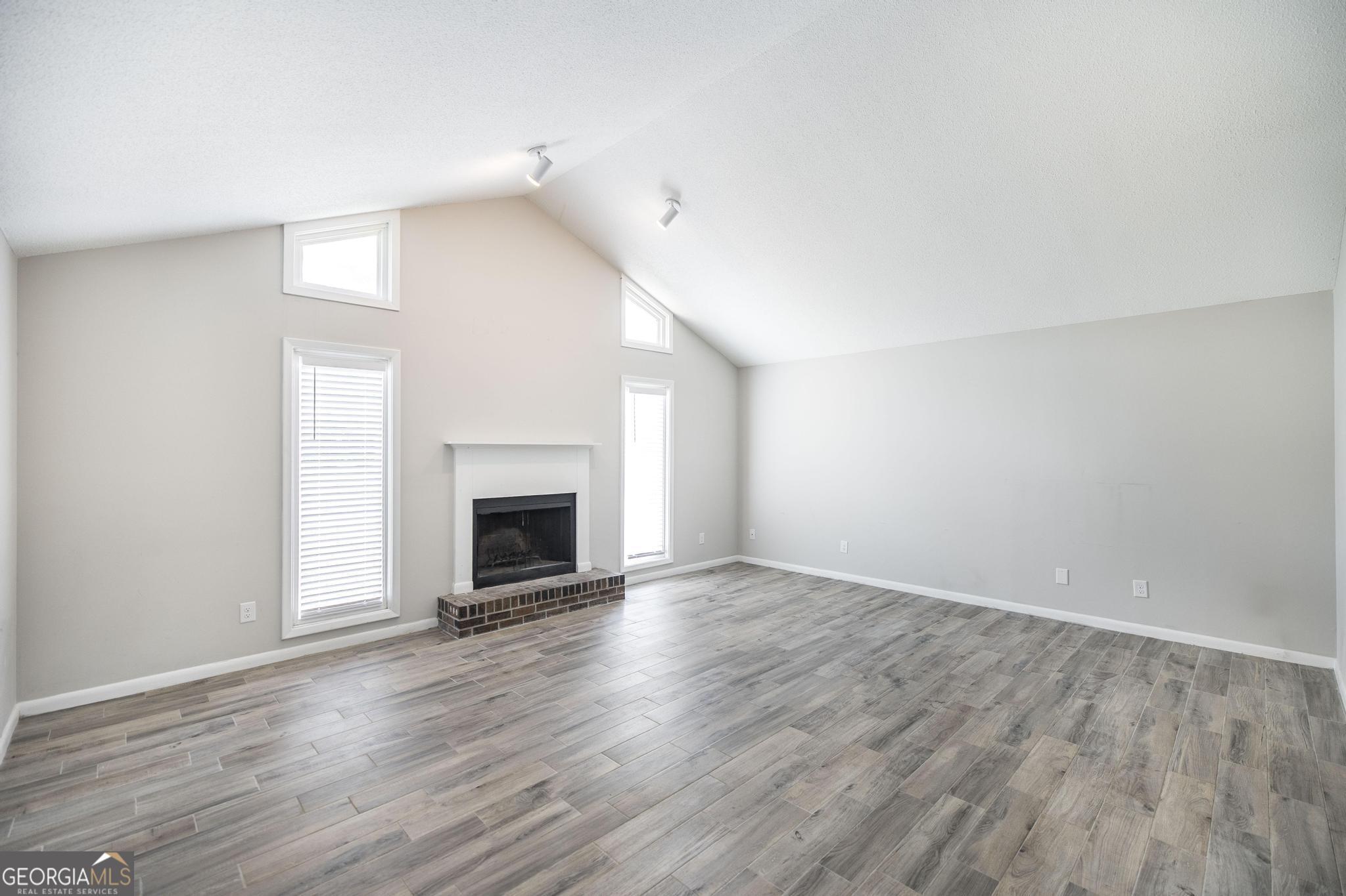 221 Gilchrist Drive Warner Robins, GA 31093 - Photo 6 of 33 an empty room with wooden floor fireplace and windows