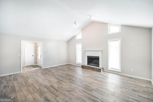 a view of an empty room with wooden floor fireplace and a window
