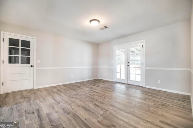 an empty room with wooden floor and windows