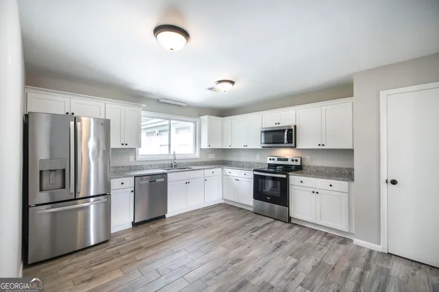 a kitchen with stainless steel appliances granite countertop a refrigerator stove a sink and dishwasher with wooden floor