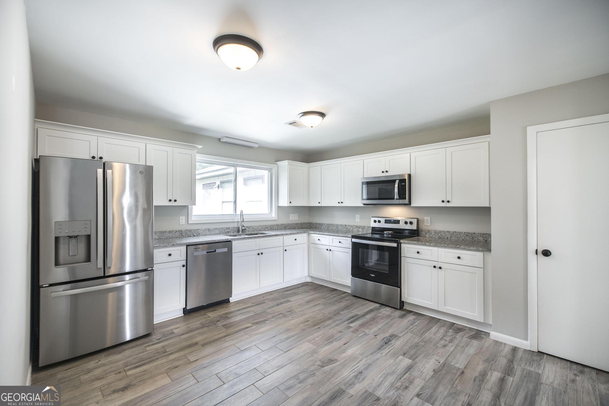 221 Gilchrist Drive Warner Robins, GA 31093 - Photo 10 of 33 a kitchen with stainless steel appliances granite countertop a refrigerator stove a sink and dishwasher with wooden floor