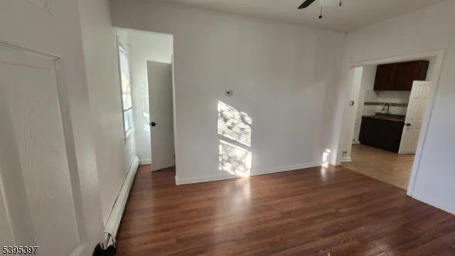 a view of an empty room with wooden floor and a cabinet