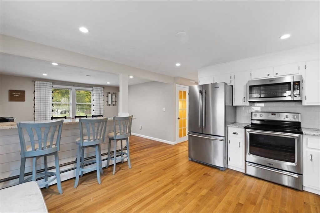 185 Temi Road Raynham, MA 02767 - Photo 14 of 33 a kitchen with stainless steel appliances granite countertop a refrigerator and a stove top oven with wooden floor