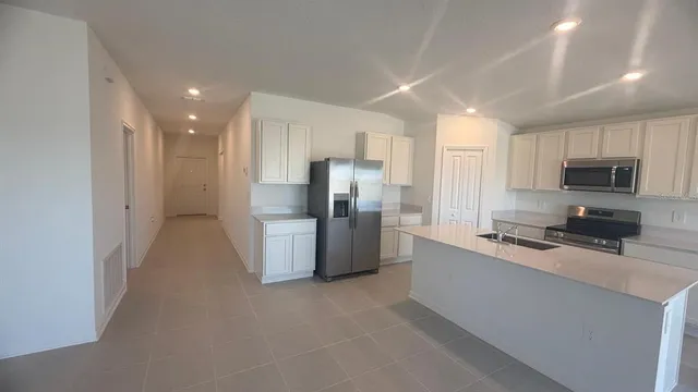 a kitchen with refrigerator a microwave a sink and cabinets