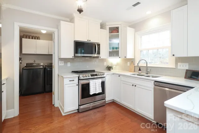 a kitchen with stainless steel appliances a microwave a stove a refrigerator and a center island with wooden floor