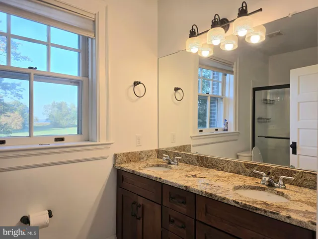 a bathroom with a granite countertop sink and a large mirror