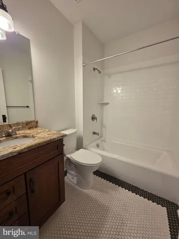 a bathroom with a granite countertop sink a toilet a mirror a bathtub and shower