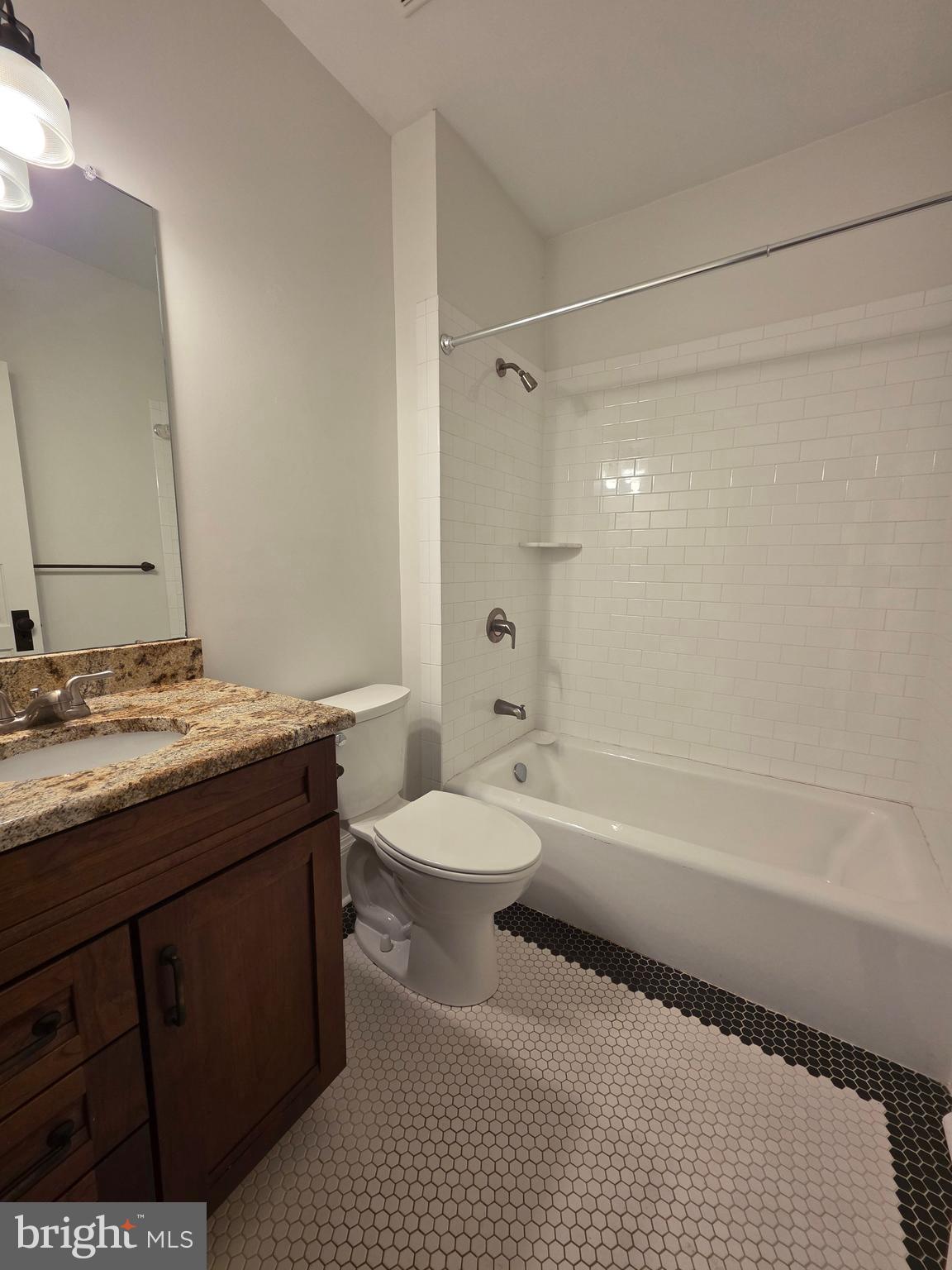 1306 B Officers Row, Unit B Delaware City, DE 19706 - Photo 9 of 10 a bathroom with a granite countertop sink a toilet a mirror a bathtub and shower