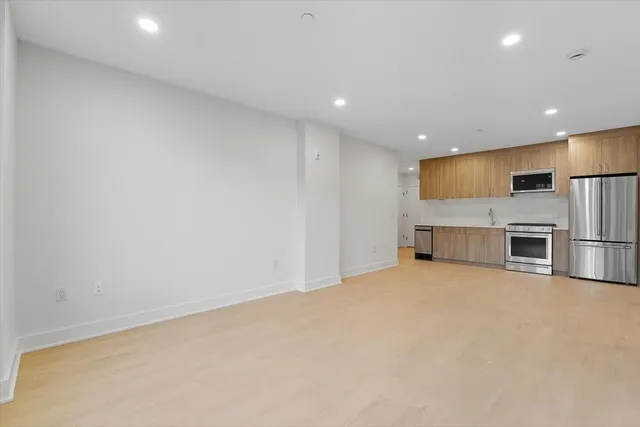 a view of kitchen with stainless steel appliances wooden floor and a refrigerator