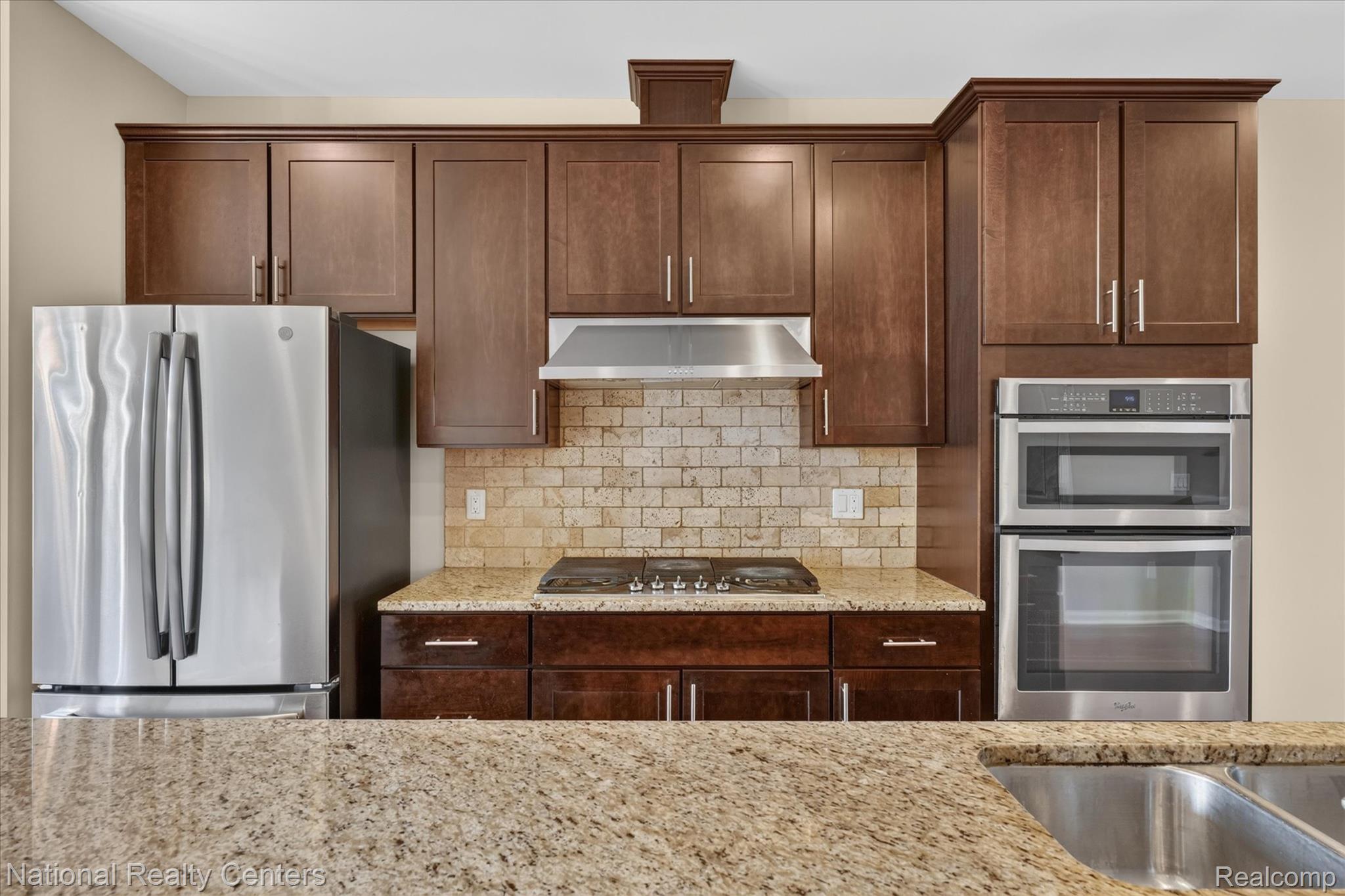 330 Glenhurst Boulevard Rochester, MI 48307 - Photo 19 of 47 Stainless steel appliances, built-in double oven, wood cabinetry, stone countertops, and a tile backsplash