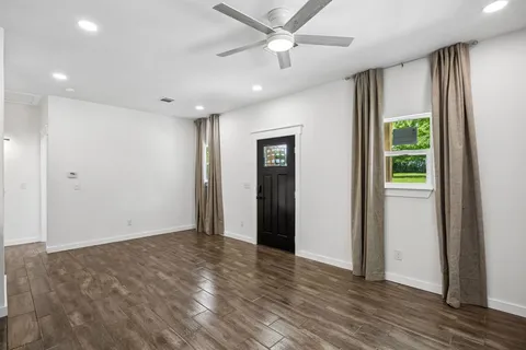 an empty room with wooden floor and a ceiling fan