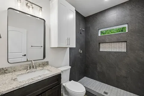 a bathroom with a granite countertop sink a toilet and a mirror