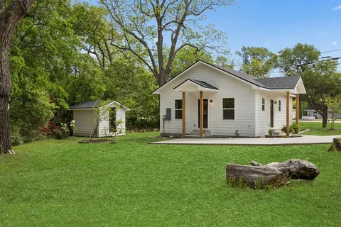 a front view of a house with a garden and trees