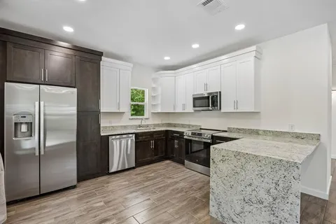 a large kitchen with stainless steel appliances granite countertop a stove a sink and a refrigerator