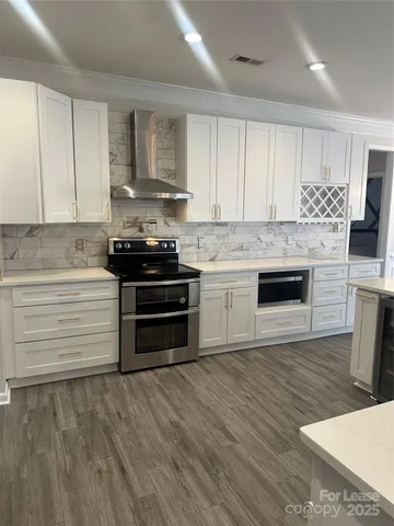 a kitchen with stainless steel appliances granite countertop a stove a sink and white cabinets