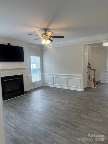 a view of a livingroom with a fireplace a ceiling fan and wooden floor