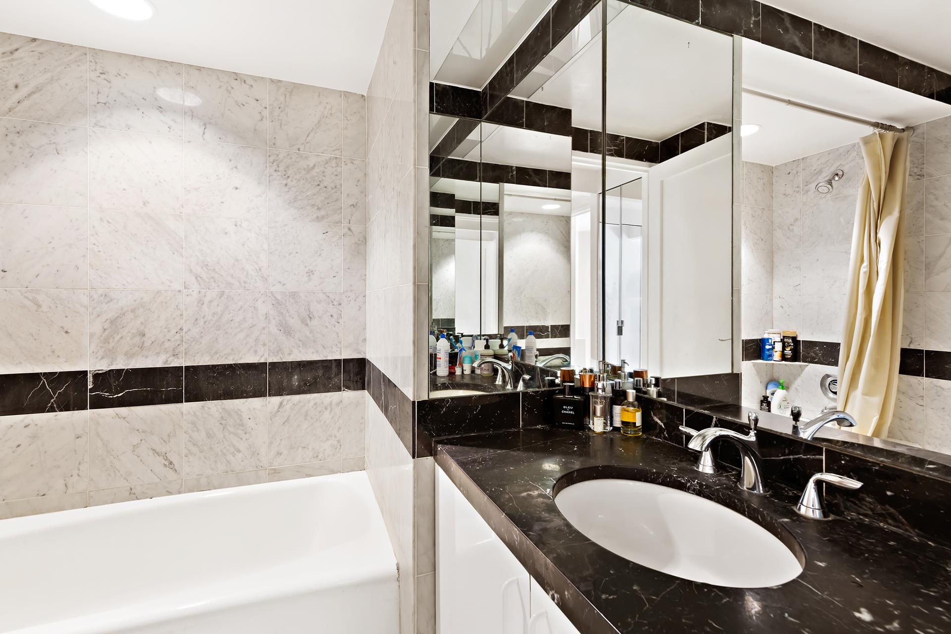 150 West 56th Street, Unit 2812 Manhattan, NY 10019 - Photo 6 of 7 a bathroom with a double vanity sink and a bathtub