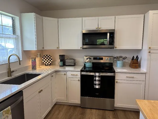 a kitchen with stainless steel appliances granite countertop a sink a stove and a microwave