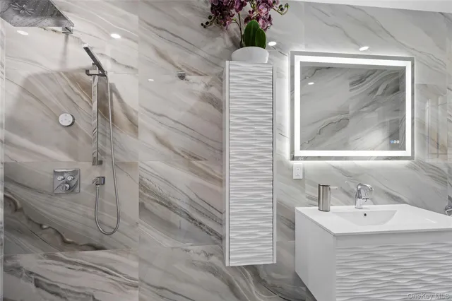 a bathroom with a sink and mirror with bathtub
