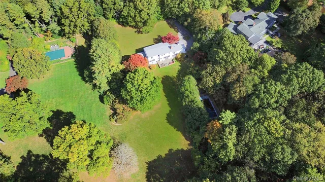 an aerial view of residential house with outdoor space and trees all around