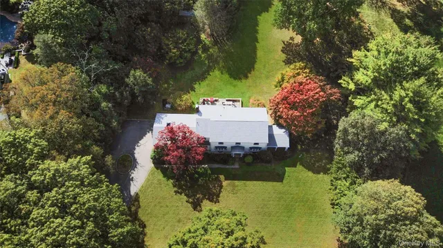an aerial view of residential house with outdoor space and trees all around