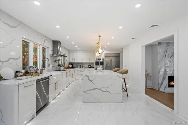 a large white kitchen with stainless steel appliances kitchen island a stove a sink a refrigerator and a counter top space