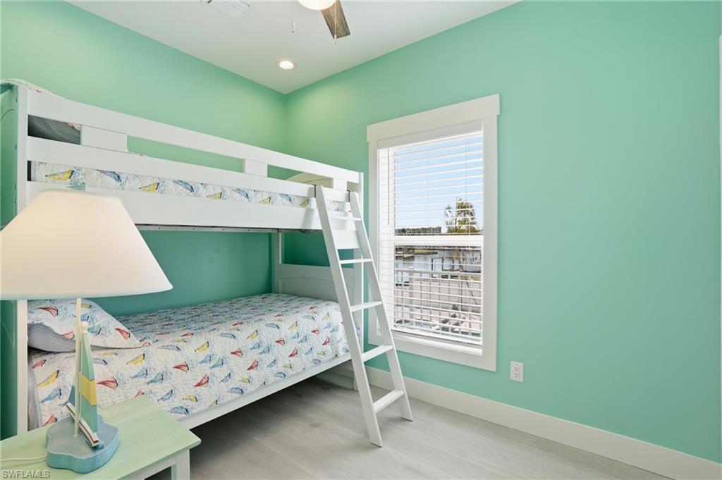 1 Fairview Boulevard Fort Myers Beach, FL 33931 - Photo 18 of 48 This room features a white bunk bed with a ladder, light green walls, and wood-finish flooring - Virtually Edited Image