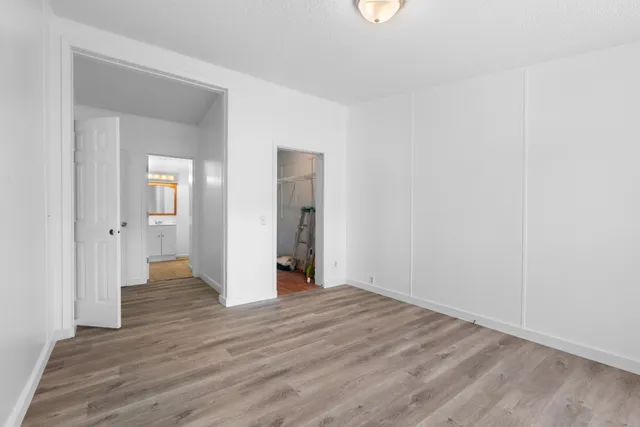 a view of an empty room with wooden floor and a mirror