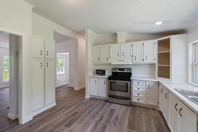 a kitchen with stainless steel appliances white cabinets and wooden floors
