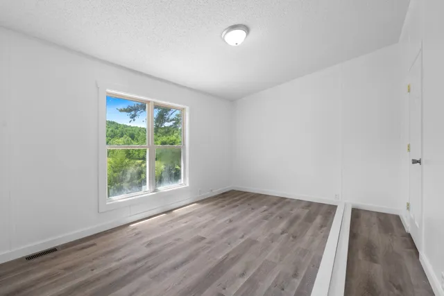 an empty room with wooden floor and windows