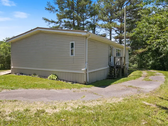 a front view of house with yard and trees in the background