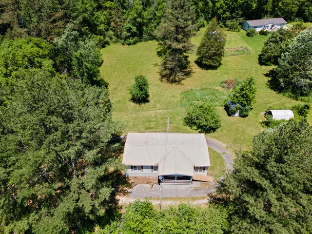 an aerial view of residential house with swimming pool and large trees