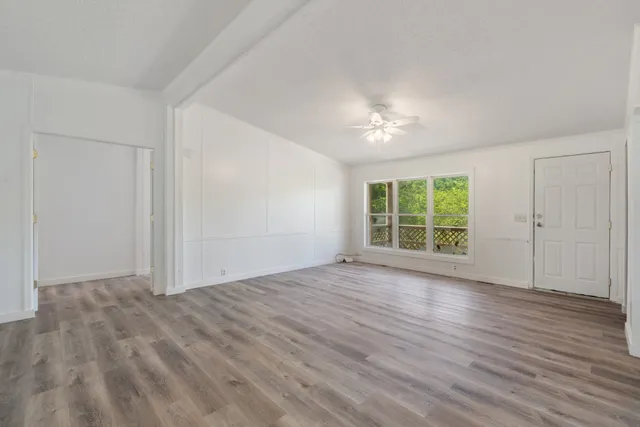a view of an empty room with wooden floor and a window