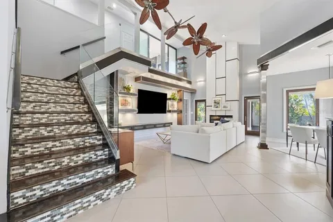 a living room with furniture a flat screen tv and floor to ceiling window