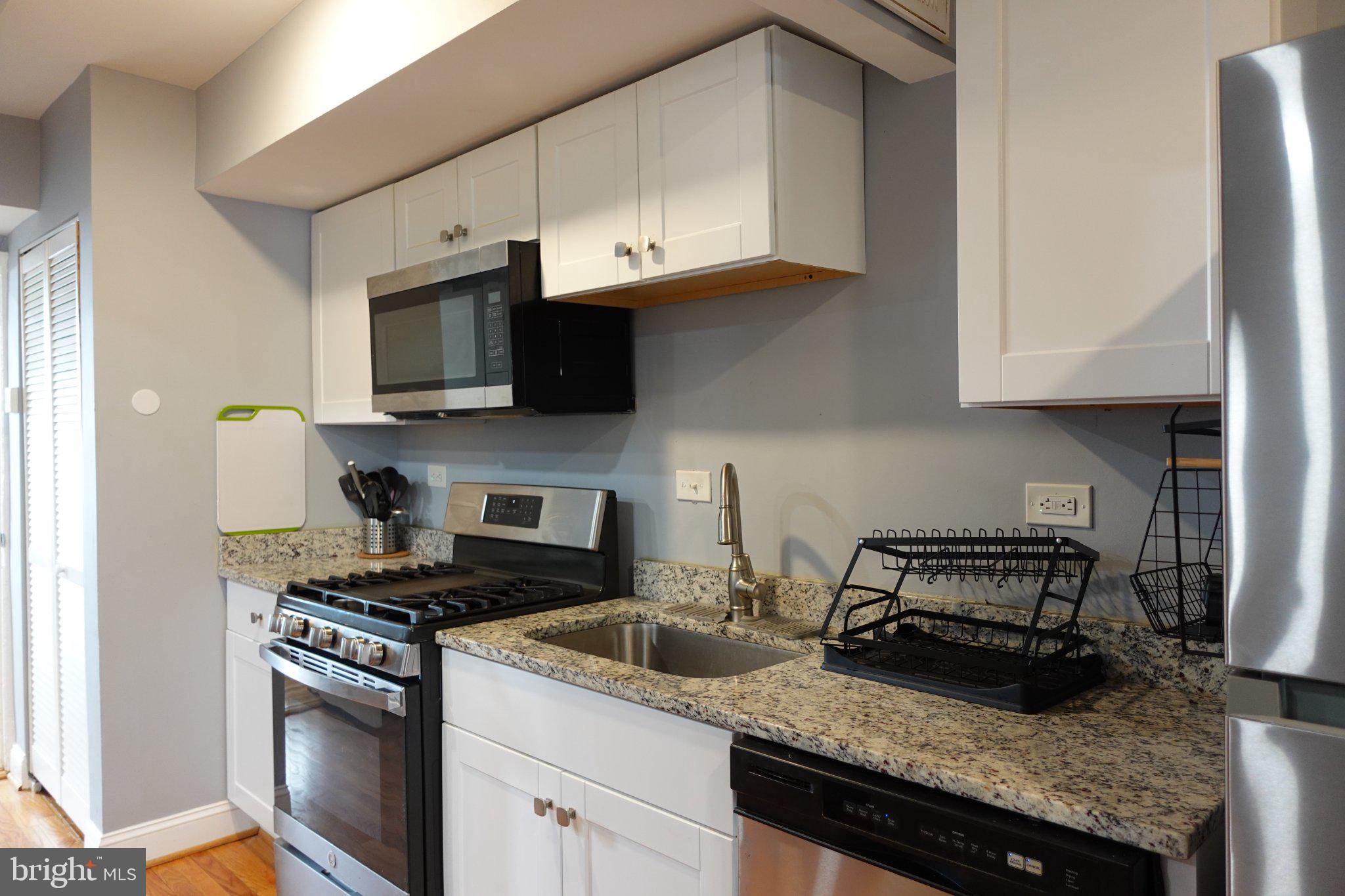 1228 18th Street Northeast Washington, DC 20002 - Photo 6 of 11 a kitchen with granite countertop stainless steel appliances a stove a sink a microwave and cabinets