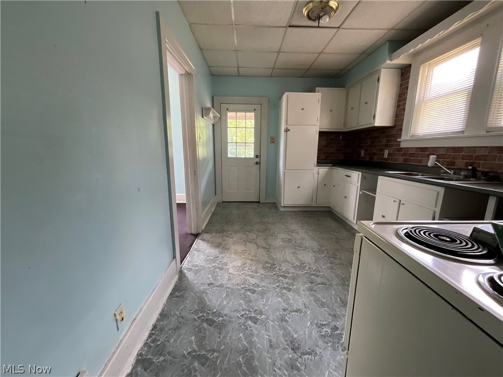 700 Cove Road Weirton, WV 26062 - Photo 7 of 26 Kitchen with stove, backsplash, a paneled ceiling, light tile floors, and sink