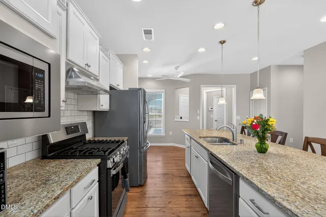 a large kitchen with stainless steel appliances granite countertop a sink a stove and a refrigerator