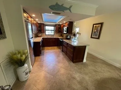 a living room with couches a flat tv screen and kitchen view with wooden floor