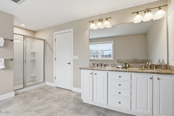 a bathroom with a granite countertop sink a mirror and a shower
