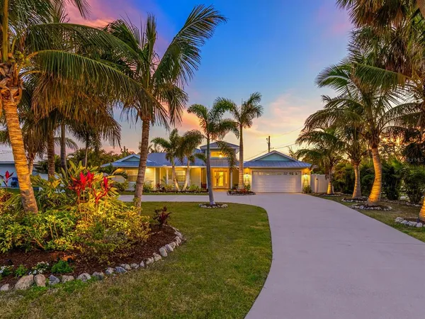 a view of a house with a yard and palm trees