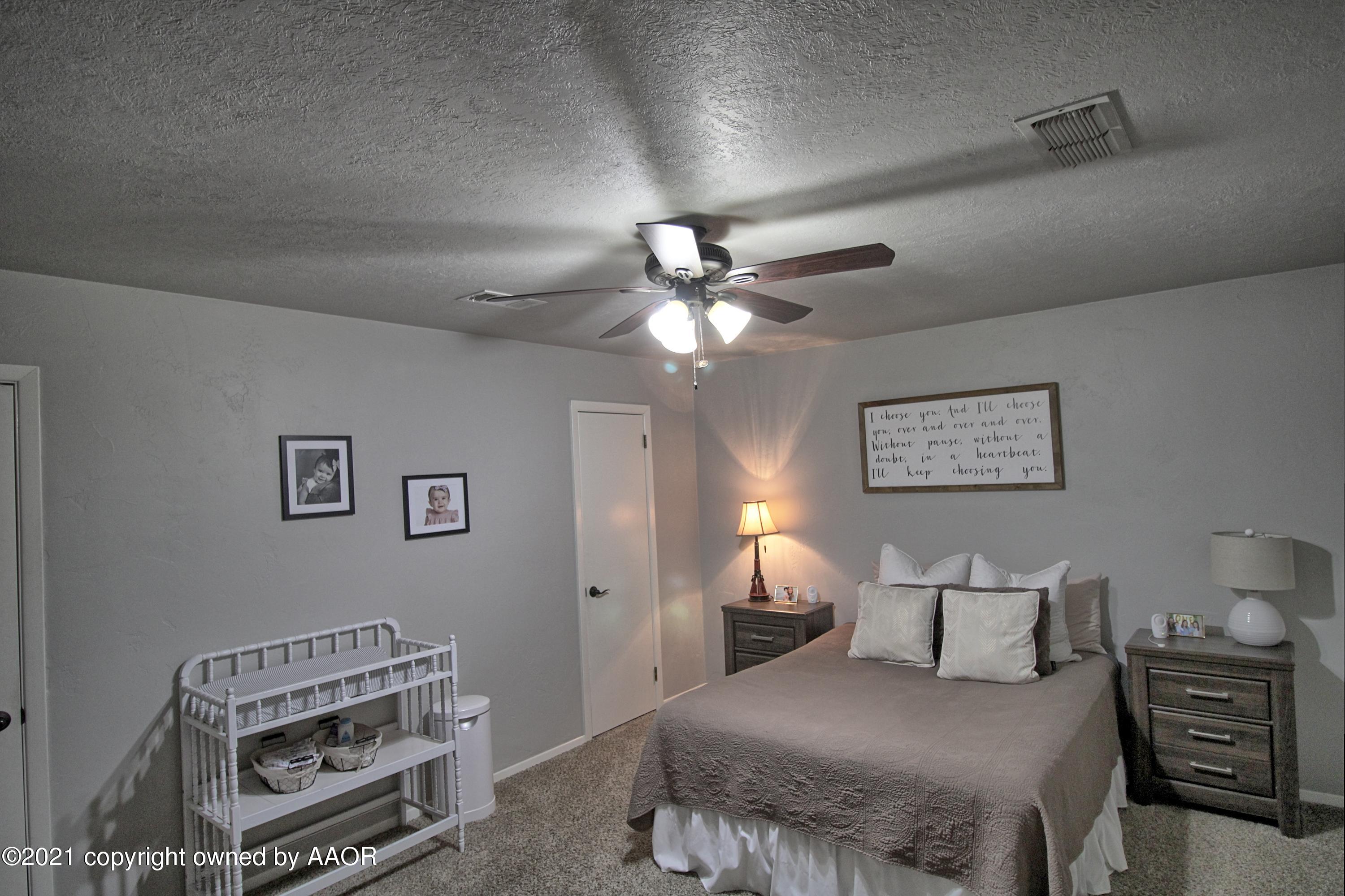 2101 Southwest 21st Avenue Perryton, TX 79070 - Photo 16 of 20 a bedroom with a bed and a chandelier