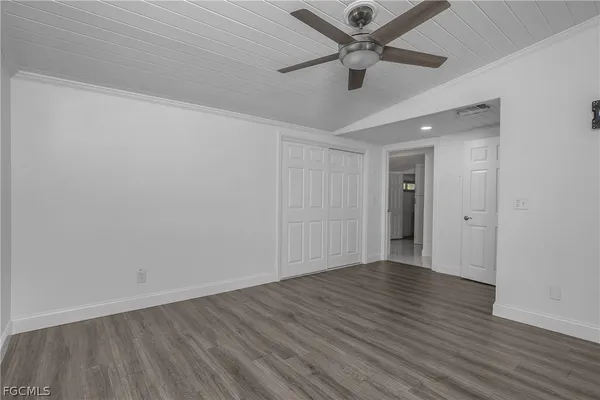an empty room with wooden floor and ceiling fan