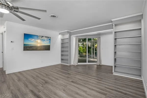 a view of an empty room with a window and wooden floor